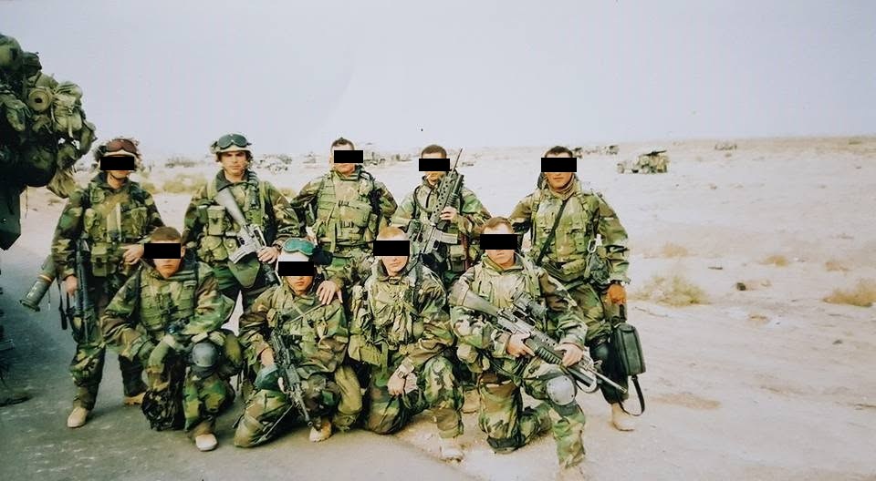 Sgt. David Scott with eight fellow Marines in desert combat gear in Iraq, 2003. The other Marines' eyes are covered with black bars.